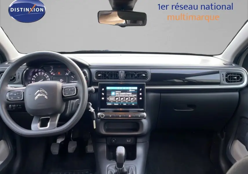 Vue frontale de l'intérieur de la Citroën C3 2022, tableau de bord noir avec écran tactile central et volant multifonction.
