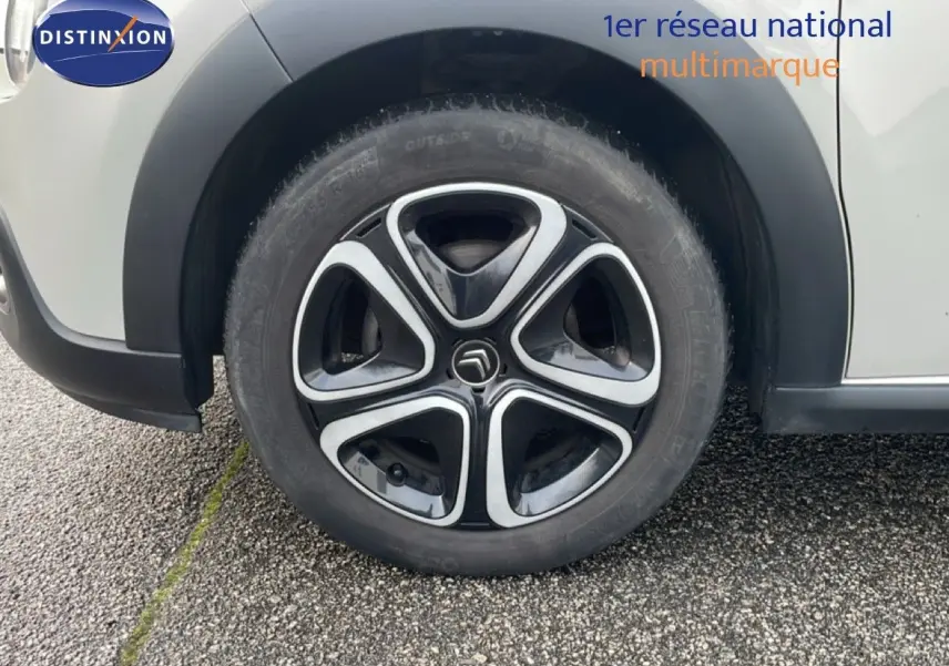Gros plan sur la roue avant gauche d'une Citroën C3 sable métal, mettant en valeur la jante noire et argentée au design distinctif.