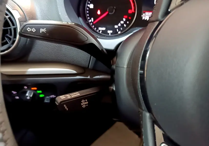 Gros plan sur le volant cuir noir et les commandes au volant de l'Audi A3 30 TDI 2019, tableau de bord partiellement visible.