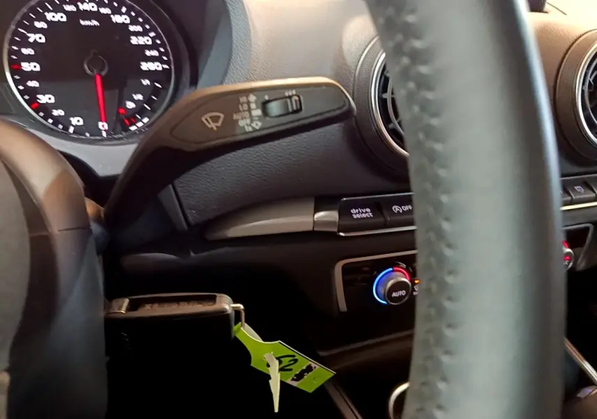 Vue intérieure centrée sur le volant cuir et la commande de climatisation bicolore d'une Audi A3 gris foncé 2019.