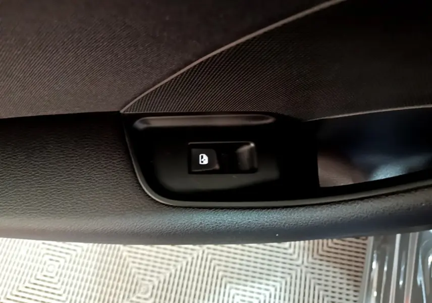 Gros plan sur le bouton de verrouillage des portes dans la portière intérieure côté conducteur de l'Audi A3 gris foncé.