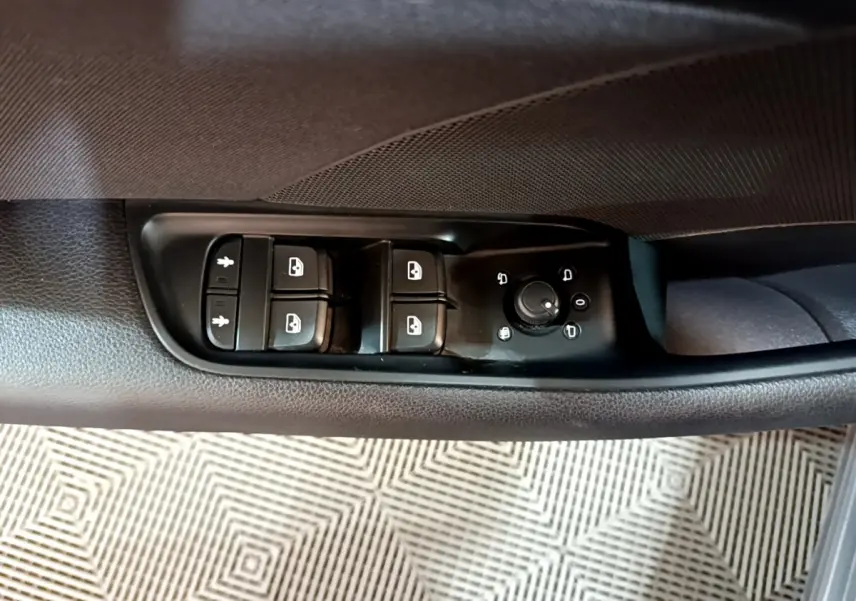 Gros plan sur les commandes de lève-vitres et réglage des rétroviseurs côté conducteur d'une Audi A3 gris foncé.