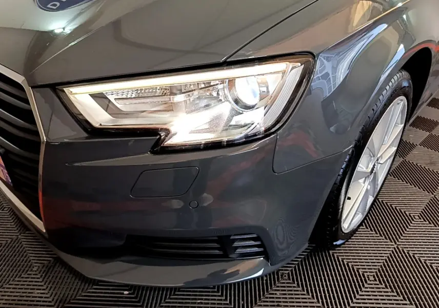 Gros plan sur l'avant droit gris foncé de l'Audi A3 30 TDI 116 S tronic avec phare LED allumé et jante visible.