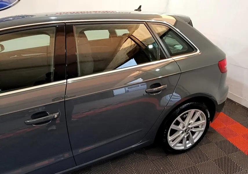 Vue latérale droite d'une Audi A3 gris foncé, mettant en valeur les jantes alliage et les lignes épurées du profil arrière.