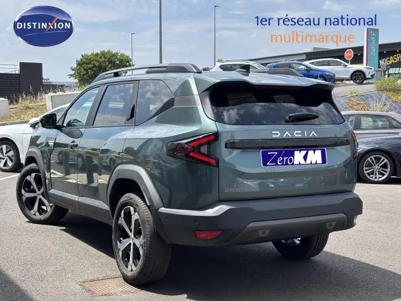 Vue 3/4 arrière droite du Dacia Bigster gris avec barres de toit et feux arrière LED en forme de flèche.