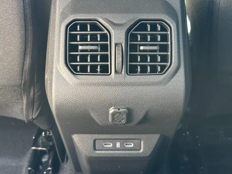 Détail des aérateurs arrière et prises USB-C du Dacia Bigster blanc, vue centrée du console arrière.