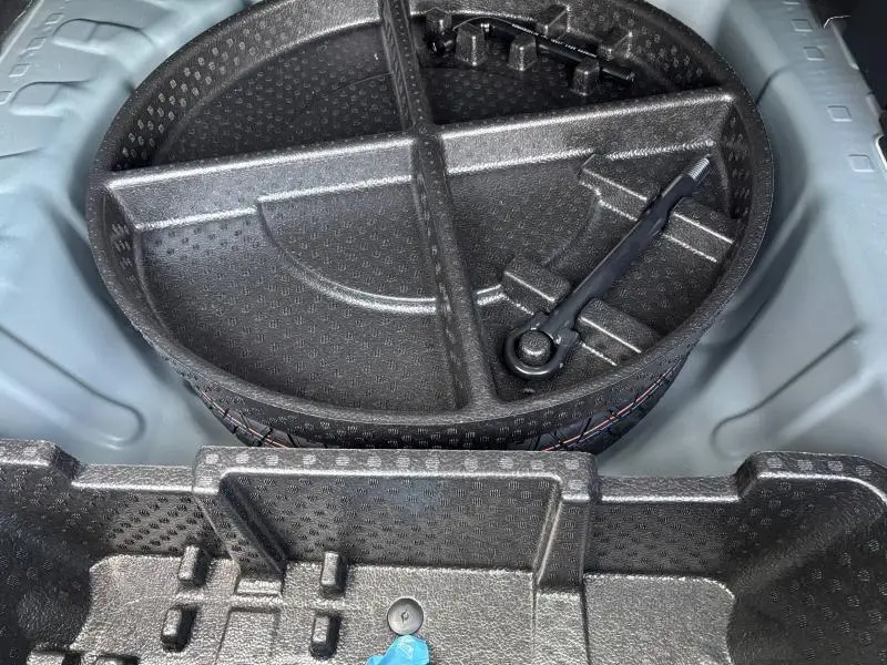 Gros plan sur le rangement sous le coffre du Dacia Bigster 2025, montrant l’organisateur noir en mousse avec outils intégrés.