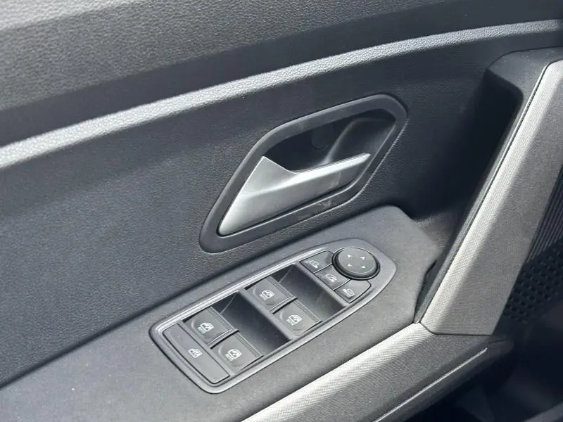 Gros plan sur la porte avant gauche du Dacia Bigster blanc, montrant la poignée argentée et les commandes des vitres électriques.