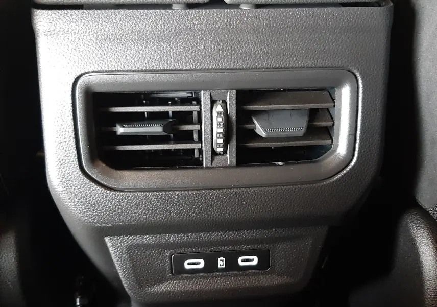 Détail intérieur du Renault Austral 2025, prise d'air arrière noire avec deux ports USB sous accoudoir cuir noir à surpiqûres bleues.