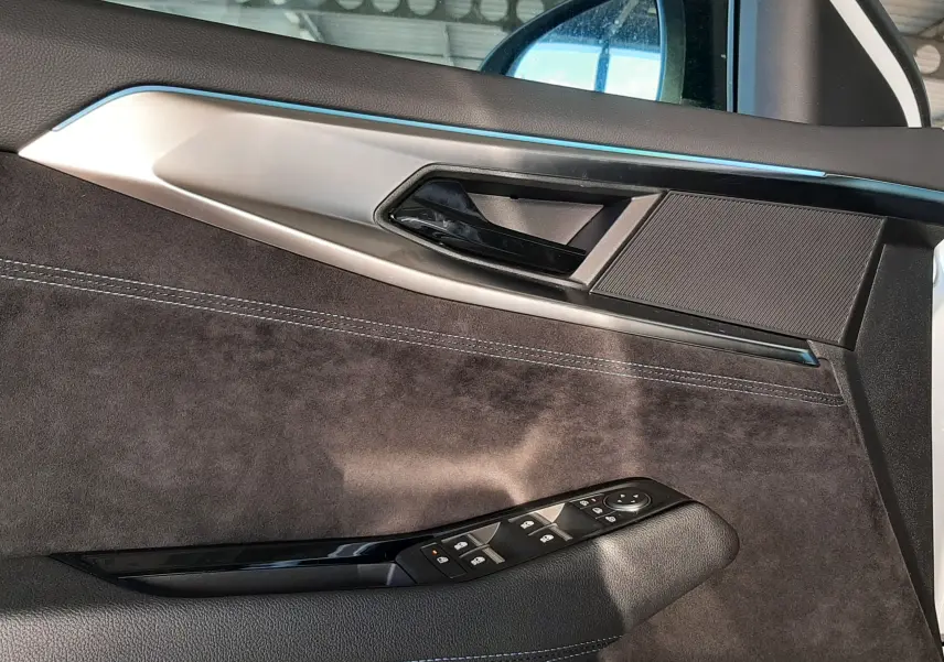 Vue intérieure côté gauche de la porte avant du Renault Austral blanc nacré, avec garniture noire et commandes de vitres.