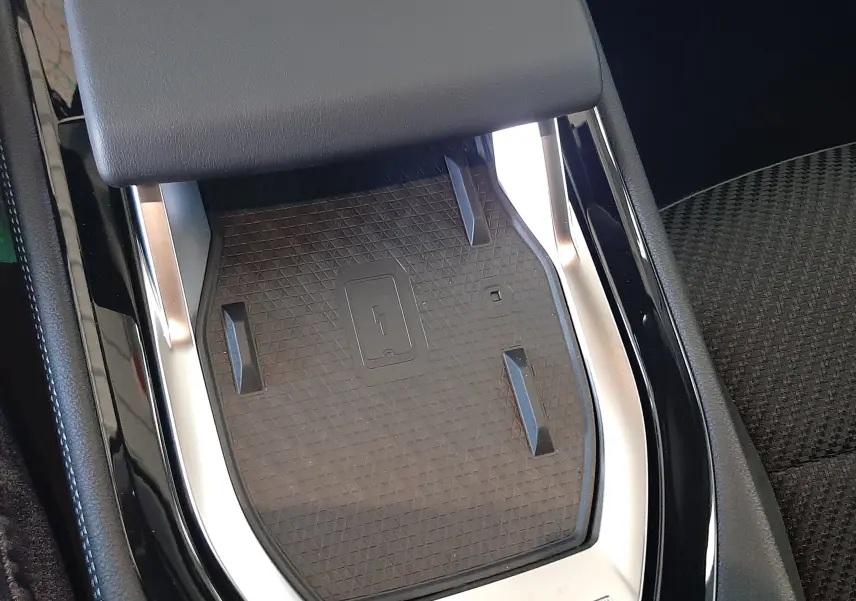 Gros plan sur le chargeur sans fil intégré à la console centrale noire du Renault Austral 2025.