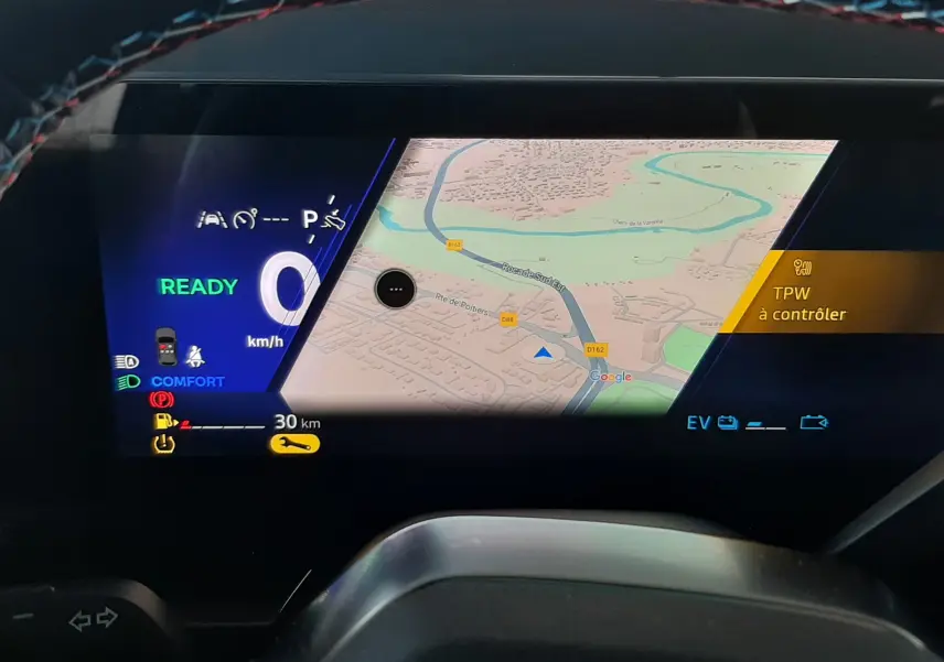 Tableau de bord numérique du Renault Austral 2025, affichant la navigation et les alertes, avec volant partiellement visible.