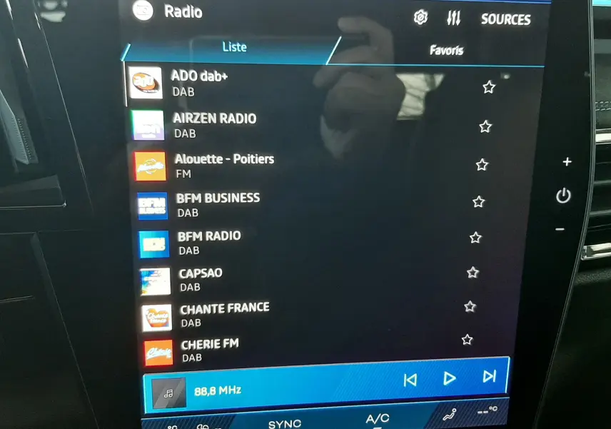 Écran tactile central affichant la liste des radios DAB dans l'habitacle du Renault Austral blanc nacré toit noir.