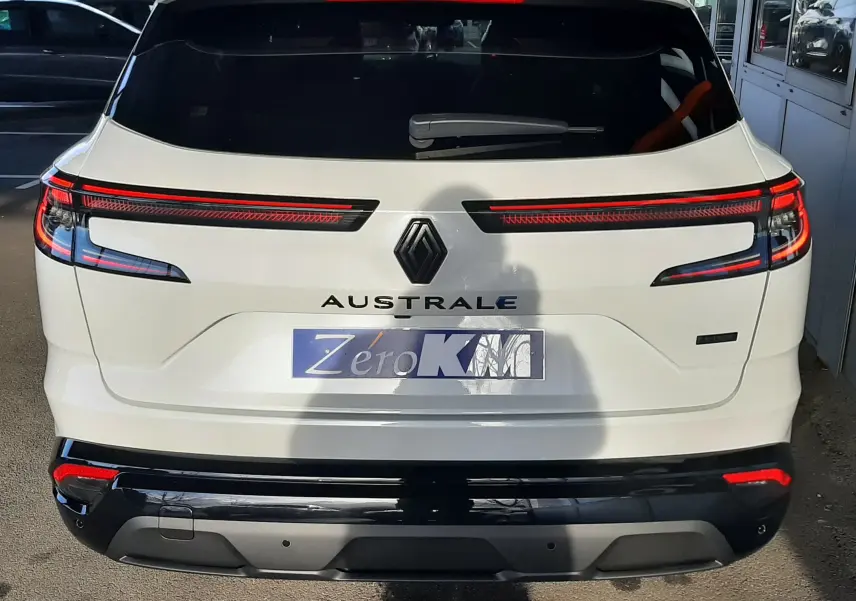 Vue arrière d'un Renault Austral blanc nacré avec toit noir, feux arrière LED étirés et hayon motorisé visible.