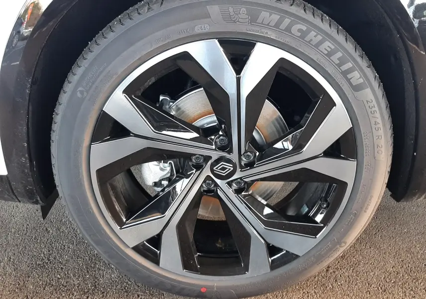 Gros plan sur la roue avant droite du Renault Austral blanc nacré avec jante alliage noire et grise au design moderne.
