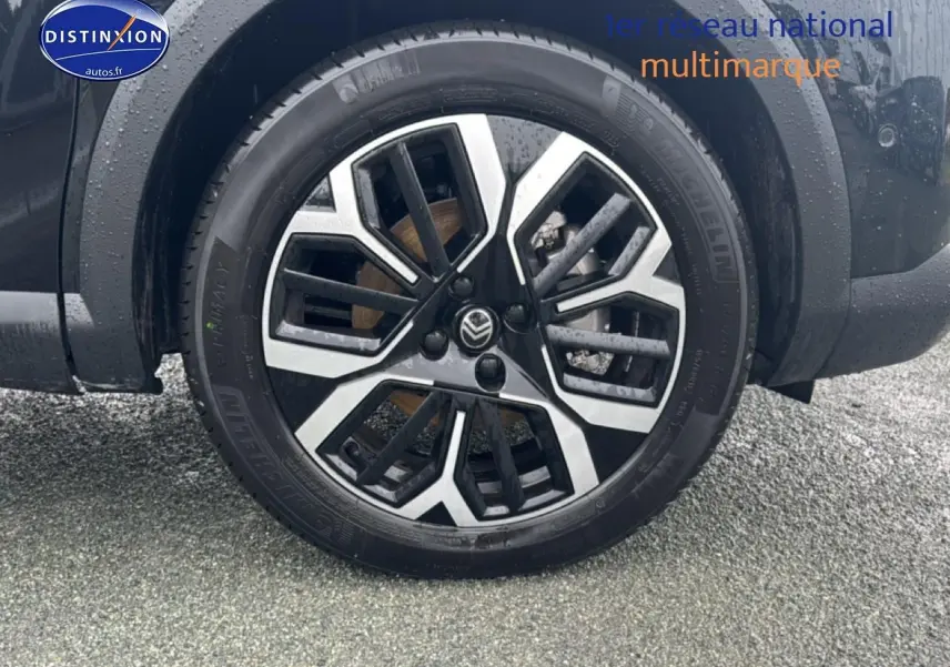 Gros plan sur la roue avant droite noire de la Citroën C4 hybride avec jante alu bicolore moderne.