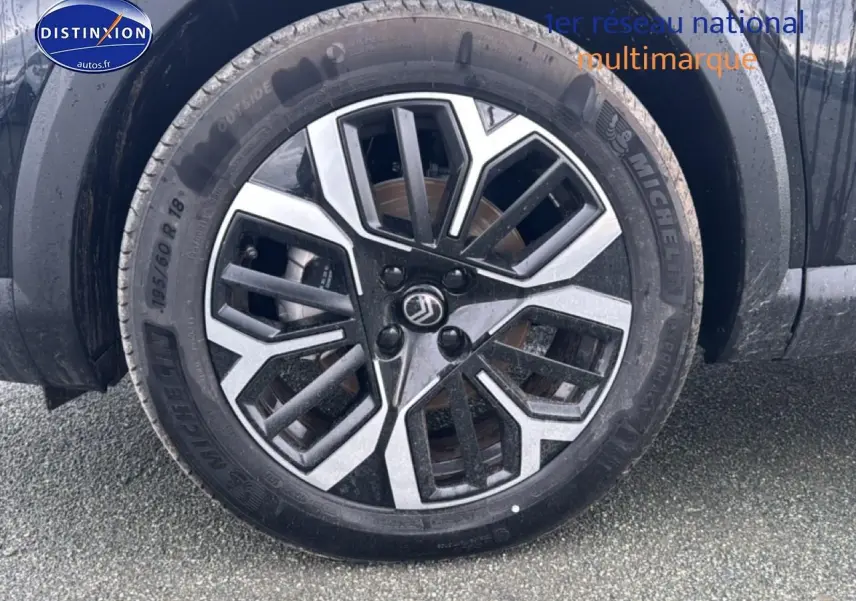 Gros plan sur la jante alu noire et argentée côté avant gauche d'une Citroën C4 noire 2025.
