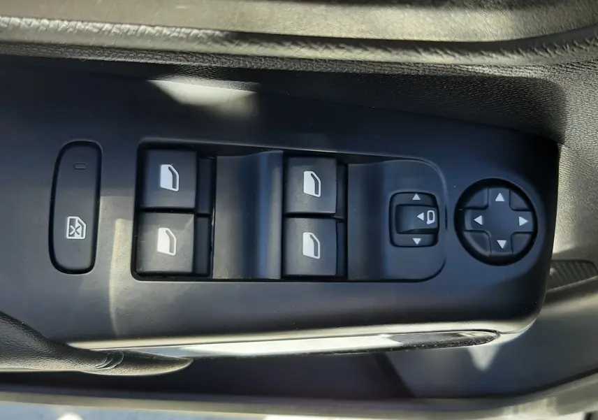 Gros plan sur les commandes de lève-vitres et réglages des rétroviseurs côté conducteur du Citroën C5 Aircross gris platinium 2025.
