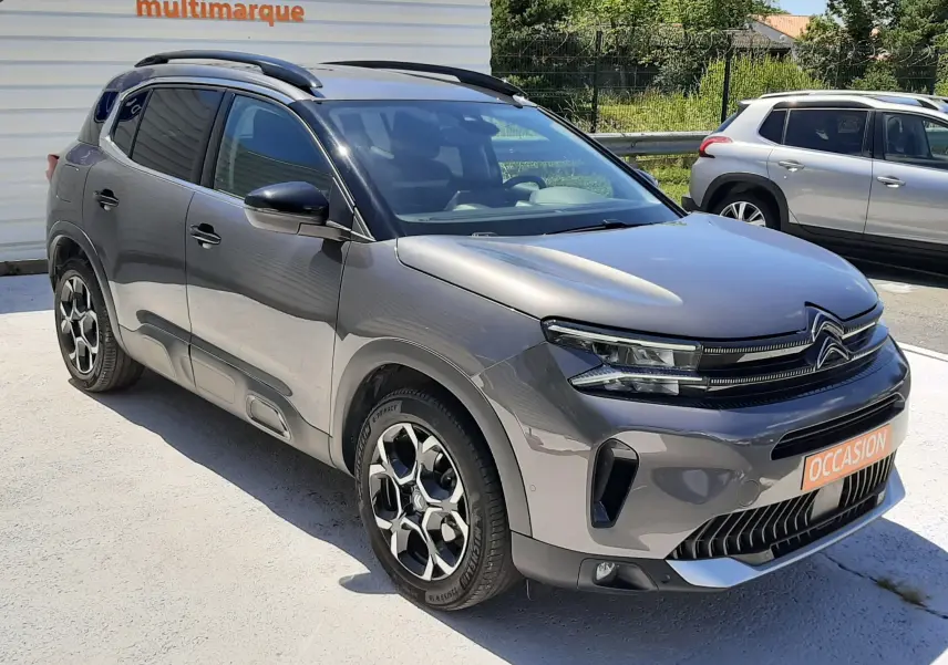 Vue 3/4 avant du Citroën C5 Aircross hybride gris platinium avec jantes bi-ton et toit noir brillant.