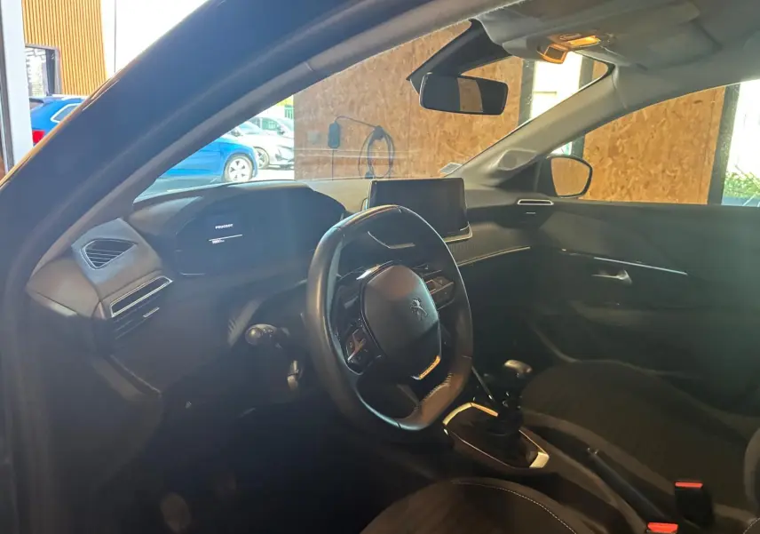 Intérieur noir de la Peugeot 208 1.5 BlueHDi 100 Style, vue côté conducteur montrant volant et console centrale.