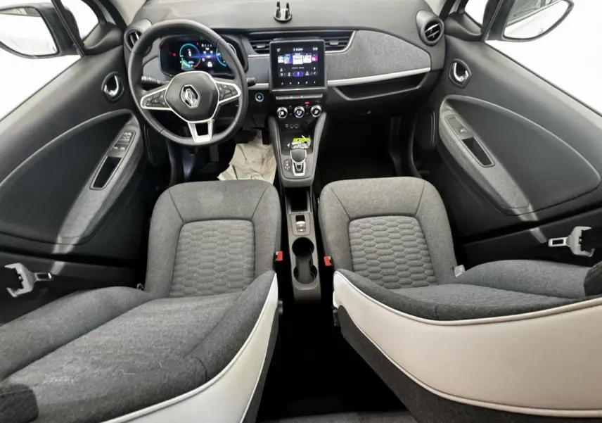 Vue intérieure avant de la Renault ZOE Iconic R135 2022 avec sièges gris et tableau de bord central tactile.