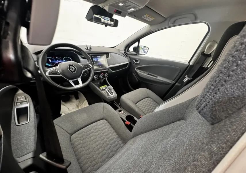 Vue intérieure avant droite de la Renault ZOE Iconic R135 2022 avec sièges gris et tableau de bord moderne.