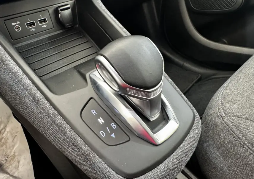 Le levier de vitesses automatique noir et argenté de la Renault ZOE Iconic R135, avec ports USB et tissu gris autour.