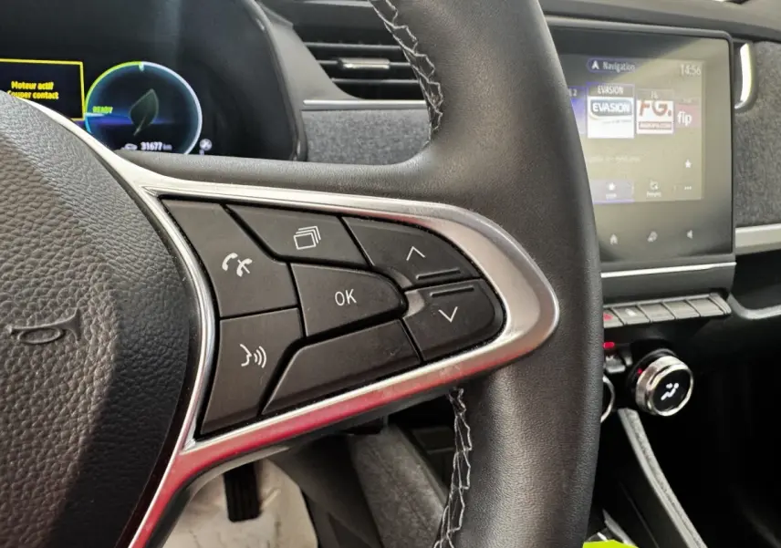 Gros plan sur le volant noir avec commandes multifonctions et écran tactile du tableau de bord de la Renault ZOE Iconic R135 blanche.