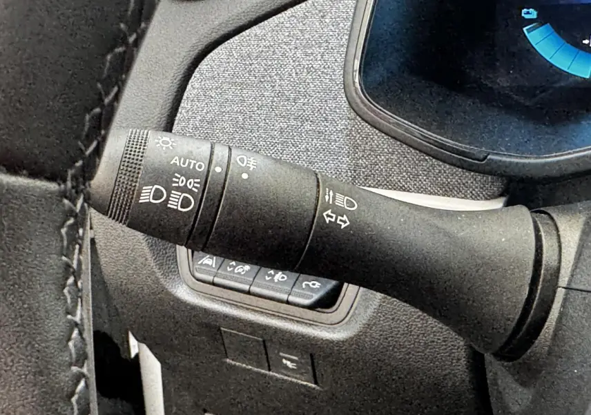 Gros plan sur la commande des phares et clignotants dans l’habitacle noir de la Renault ZOE blanche Iconic R135.