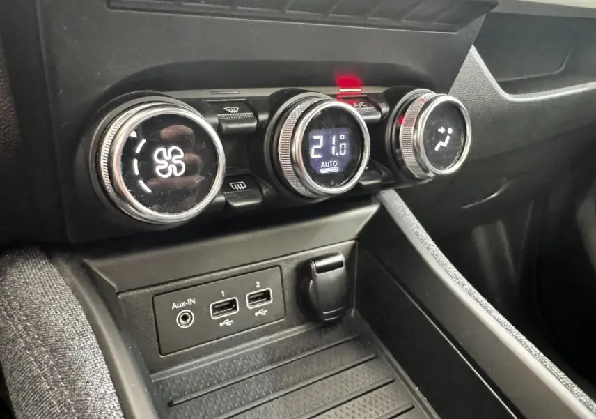 Gros plan sur la console centrale de la Renault ZOE blanche, montrant les commandes de climatisation et ports USB.