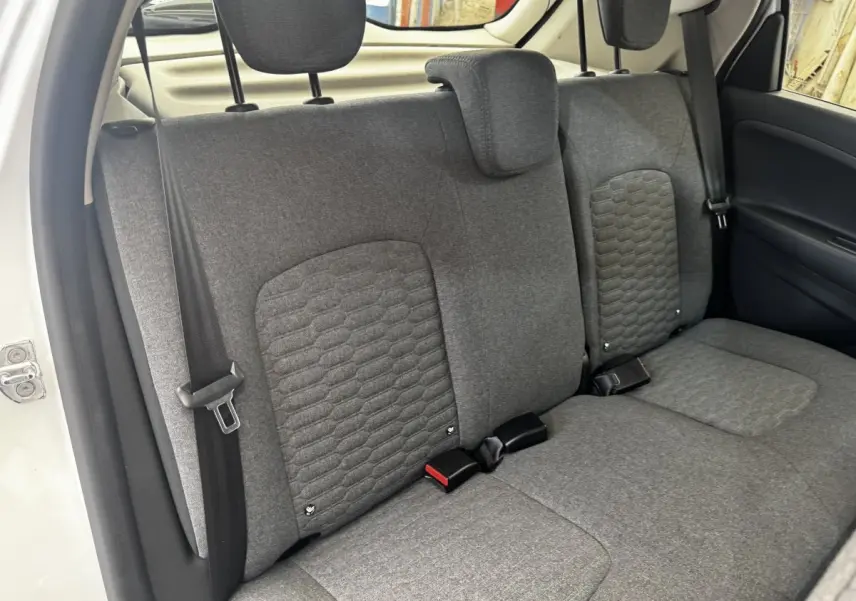 Vue intérieure sur la banquette arrière grise de la Renault ZOE blanche, avec appuie-têtes et ceintures visibles.
