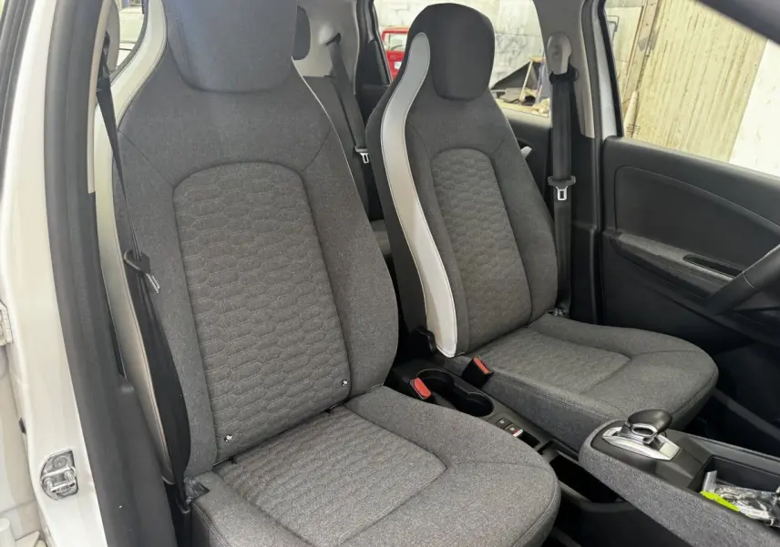 Vue intérieure côté gauche sur les sièges avant gris de la Renault ZOE Iconic R135 blanche 2022.