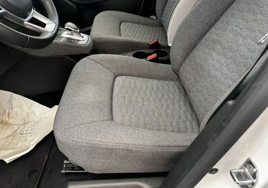 Vue intérieure côté conducteur de la Renault ZOE blanche, sièges avant gris tissu avec console centrale et levier de vitesse.
