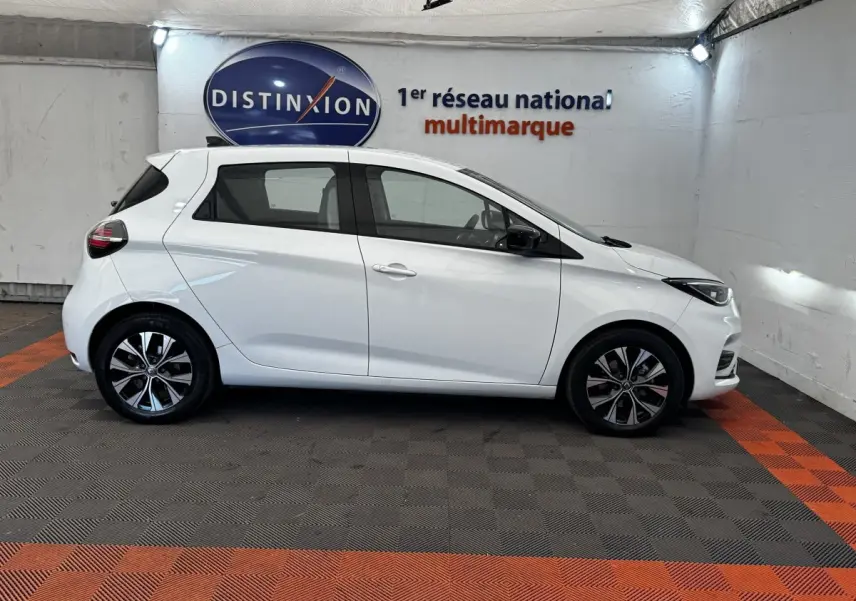 Profil côté gauche d'une Renault ZOE blanche Iconic R135 2022, avec jantes alliage et rétroviseurs noirs.