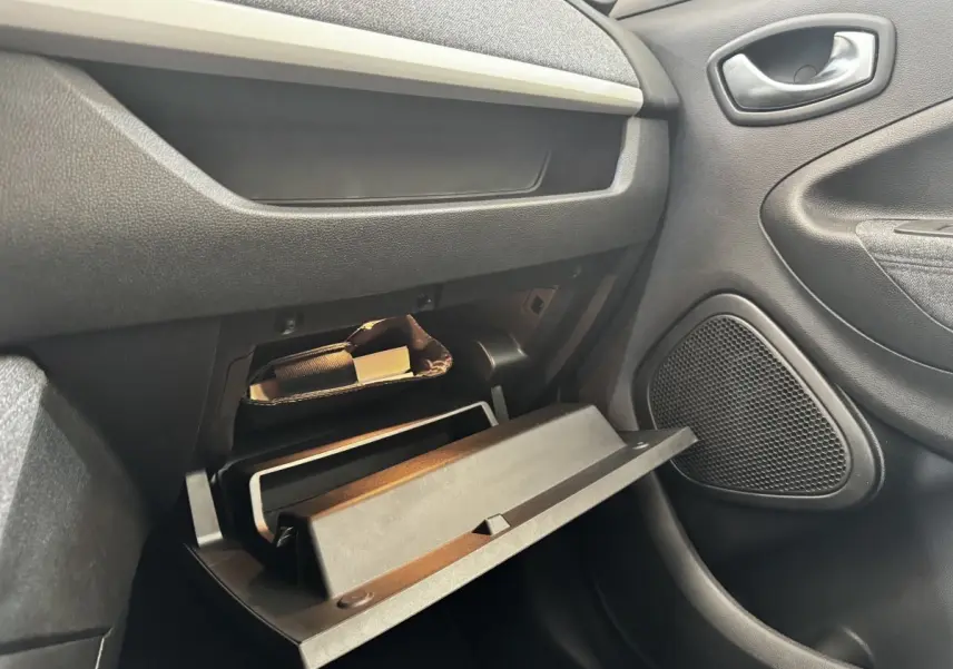 Vue intérieure côté passager de la boîte à gants ouverte de la Renault ZOE blanche, montrant le rangement et la porte.