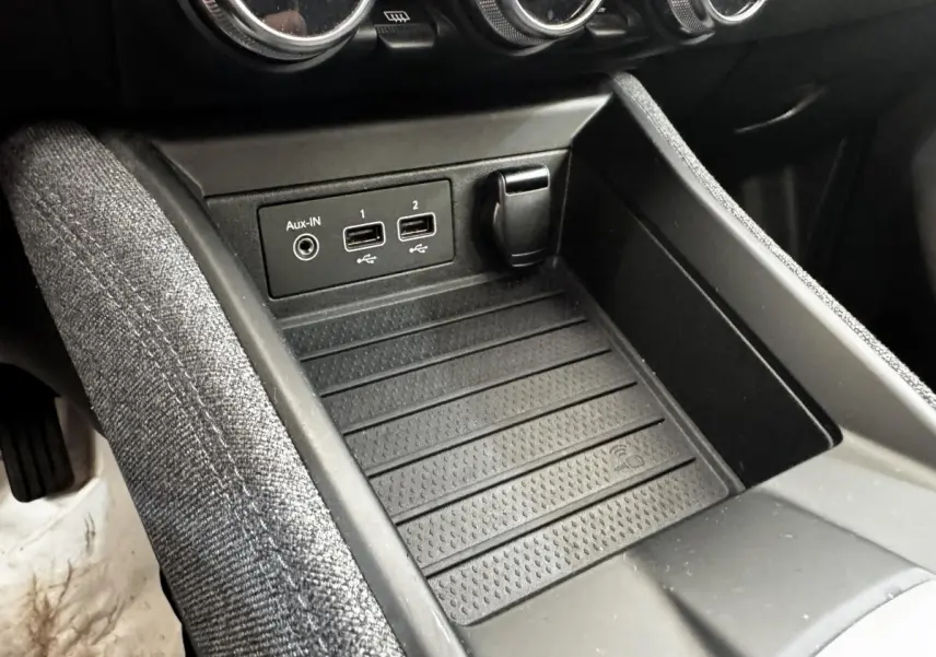 Gros plan sur la console centrale noire de la Renault ZOE blanche, montrant ports USB, prise Aux-IN et rangement.
