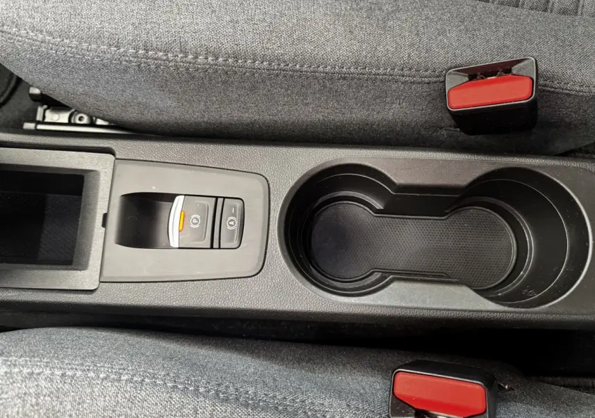 Gros plan sur la console centrale noire avec porte-gobelets et bouton de frein à main électrique de la Renault ZOE blanche.