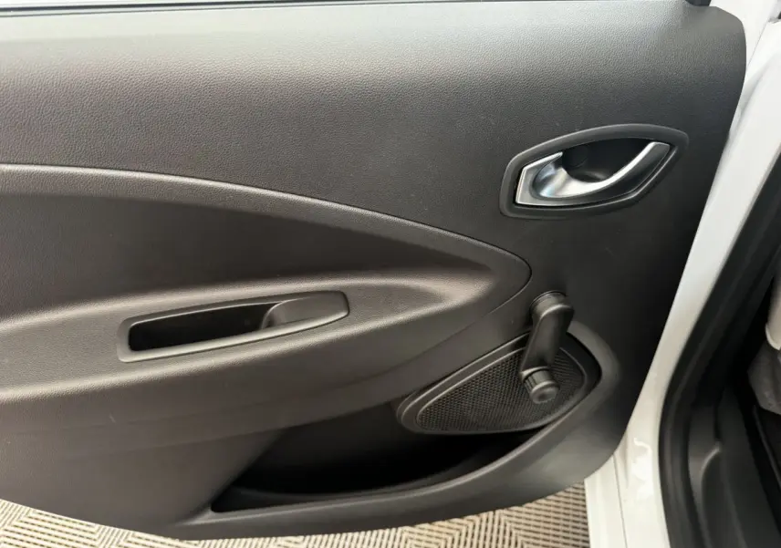 Gros plan sur la porte arrière droite blanche de la Renault ZOE Iconic R135 avec manivelle de vitre noire.