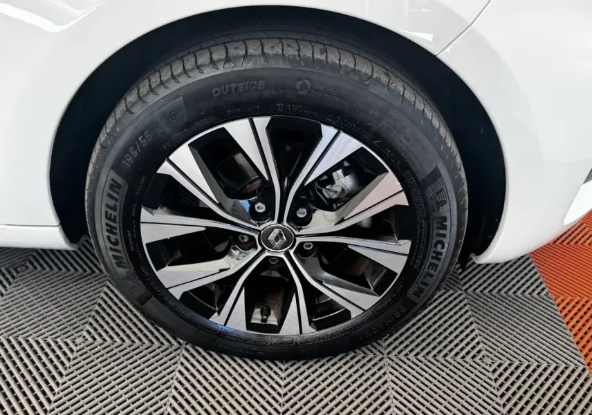 Gros plan sur la roue avant droite de la Renault ZOE blanche, jante alliage bicolore avec logo Renault au centre.