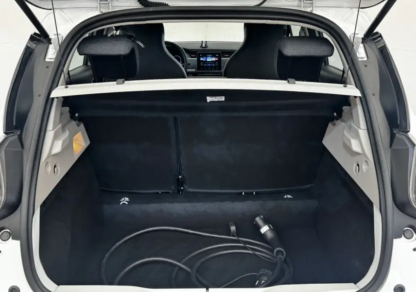 Vue arrière du coffre ouvert d'une Renault ZOE blanche, avec câble de recharge électrique visible à l'intérieur.