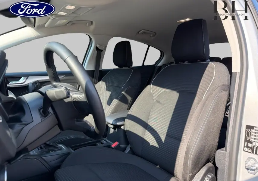 Intérieur avant de la Ford Focus 2023 gris Lunaire, vue côté conducteur avec sièges tissu noir et volant cuir.