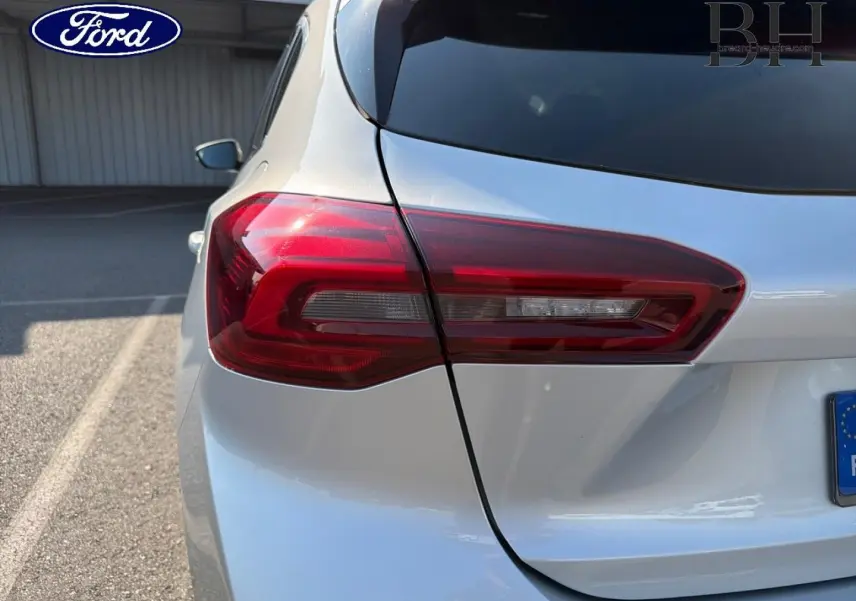 Gros plan sur le feu arrière gauche d'une Ford Focus 2023 gris lunaire métallisé, avec partie de la lunette arrière visible.