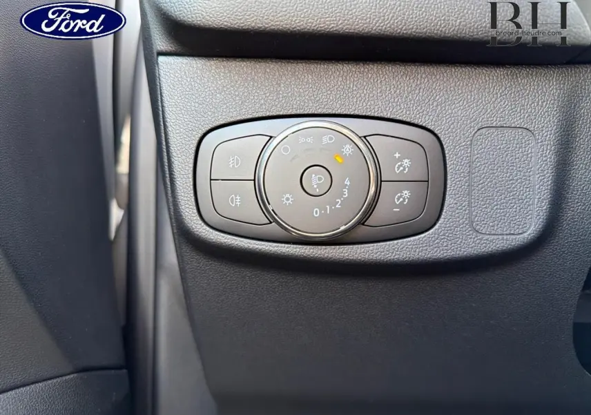Gros plan sur la commande d'éclairage noire à gauche du tableau de bord d'une Ford Focus 2023 gris lunaire métallisé.