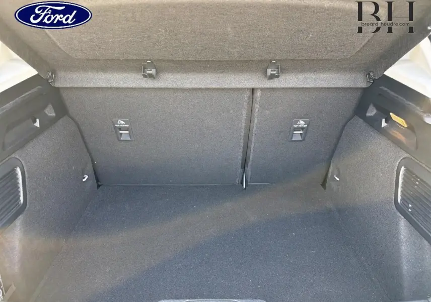 Coffre ouvert de Ford Focus 2023 gris lunaire, vue intérieure montrant l'espace de chargement et les fixations Isofix.
