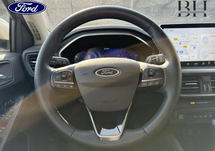 Vue rapprochée du volant cuir multifonction de la Ford Focus 2023 avec tableau de bord numérique et écran tactile.