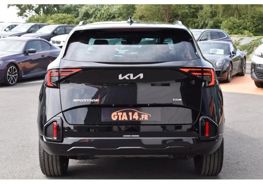 Vue arrière d'un Kia Sportage noir 2026 avec feux arrière LED et logo KIA visible sur un parking.