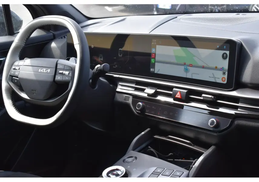 Vue intérieure du tableau de bord du Kia Sportage hybride 2026, avec écran tactile large et volant multifonction noir.