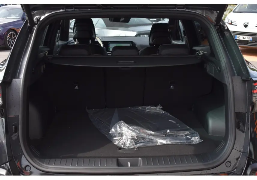 Coffre ouvert vu de l’arrière d’un Kia Sportage noir 2026, avec plancher plat et cache-bagages visible.
