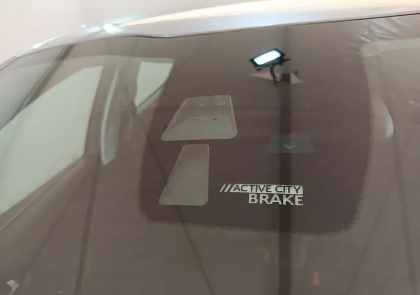 Gros plan sur le pare-brise d’une Peugeot 208 gris clair, mettant en valeur le système Active City Brake.