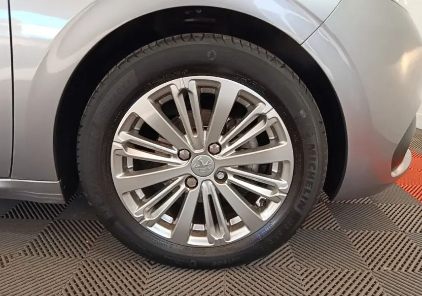 Gros plan sur la roue avant droite gris clair d’une Peugeot 208 Puretech 82 Allure avec jante alliage multibranches.